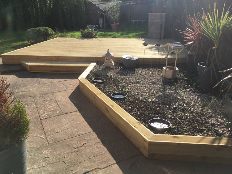 Wooden flower bed and decking by neat borders landscape gardening